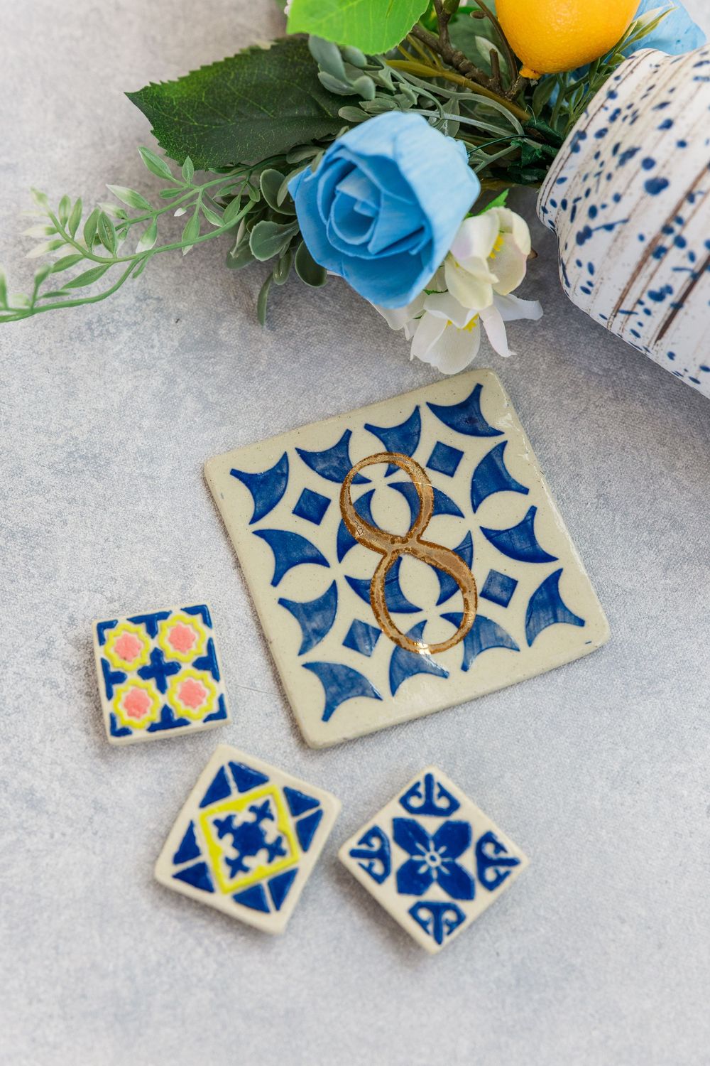 Blue and white decorative ceramic tiles with floral patterns displayed alongside a blue rose arrangement.