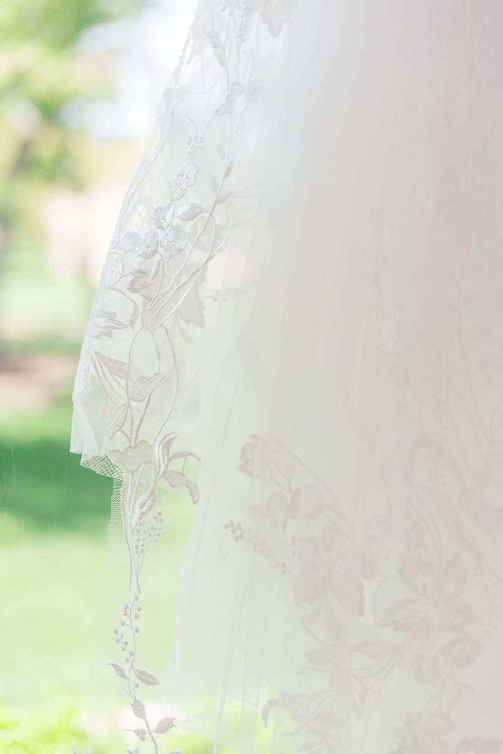 Close-up detail of delicate lace patterns on a white wedding veil with soft natural lighting.