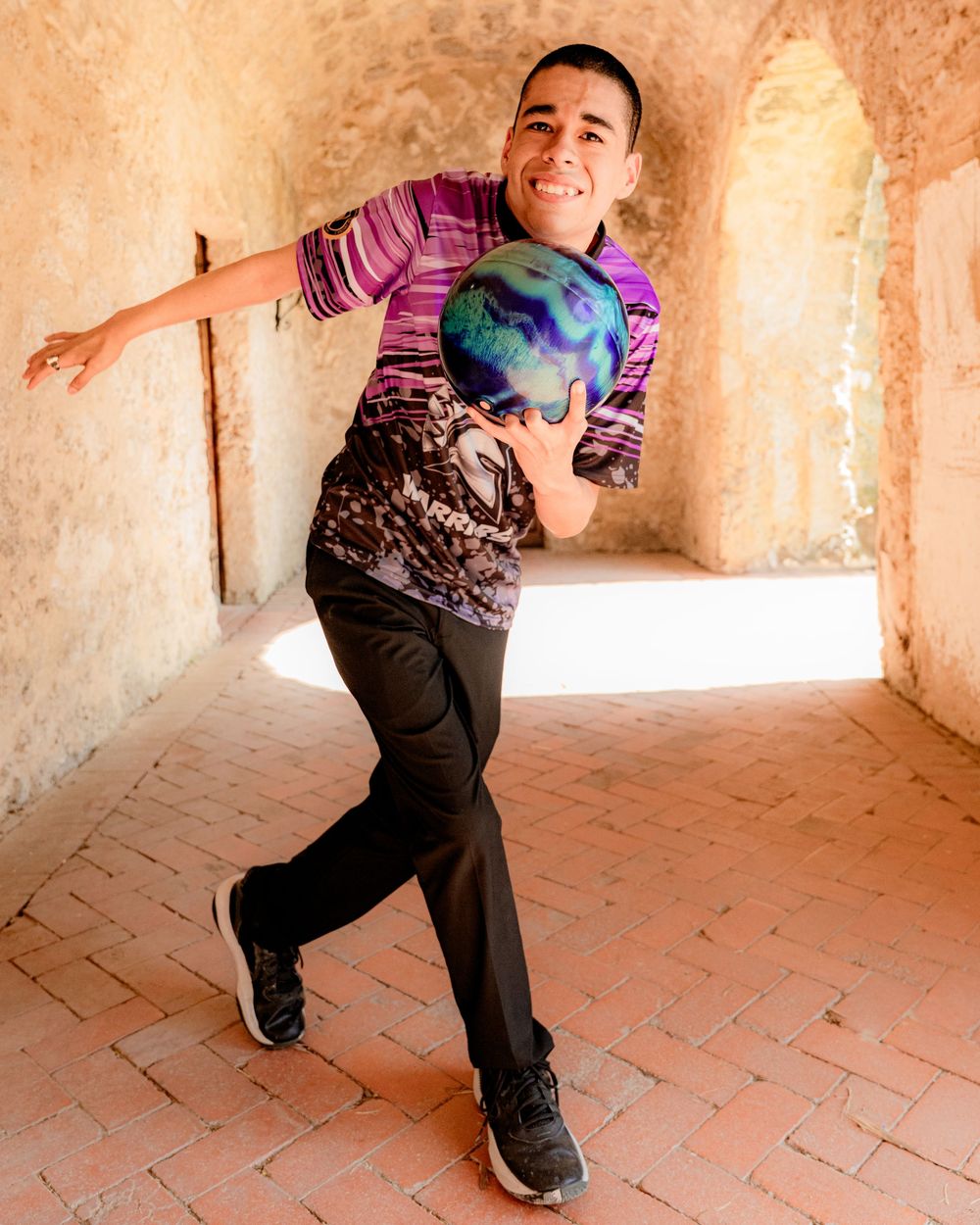 A person poses playfully with a globe in a terracotta archway.