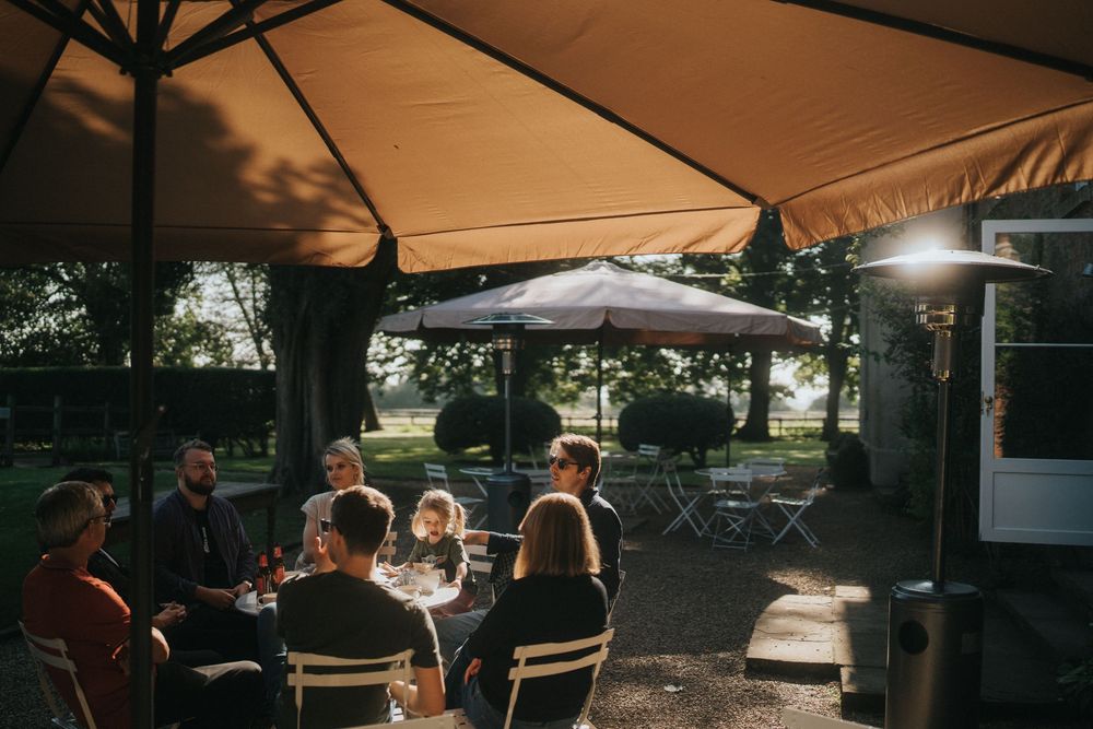 People gather under outdoor canopies during a sunset or golden hour event in a backyard setting at Aswarby Rectory.