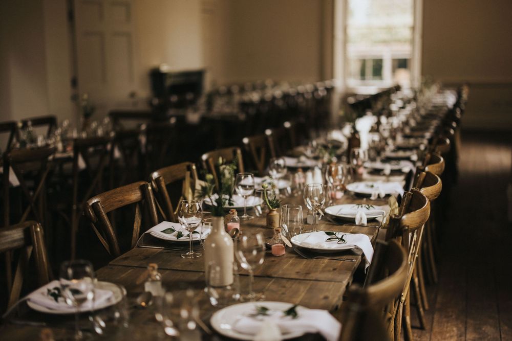 A long rustic wooden dining table set for a formal dinner with place settings and glassware at Aswarby Rectory.