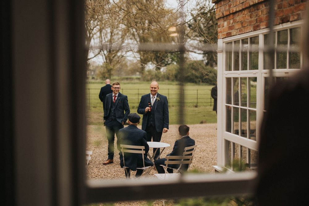 Wedding party participants converse in a relaxed outdoor garden setting during autumn at Aswarby Rectory.
