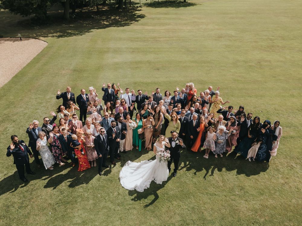 Aerial view of a large wedding party gathered on a lush green lawn at Rise Hall. Taken by Grimsby photographers.