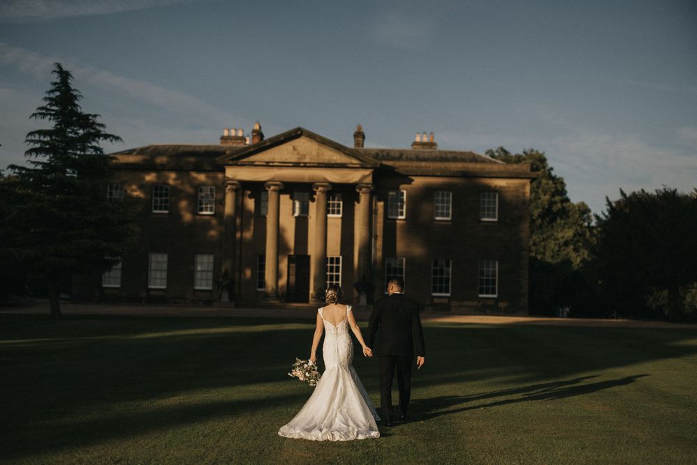 Elegant wedding photo captured at dusk in front of Rise Hall on a manicured lawn.
