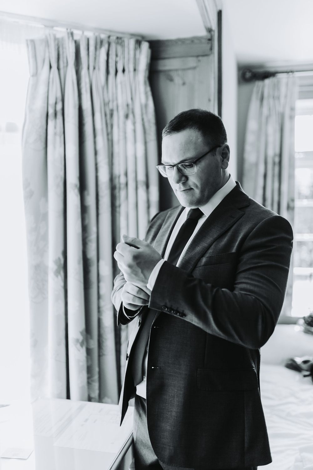 Black and white photograph of formal attire preparations inside a bright hotel room.
