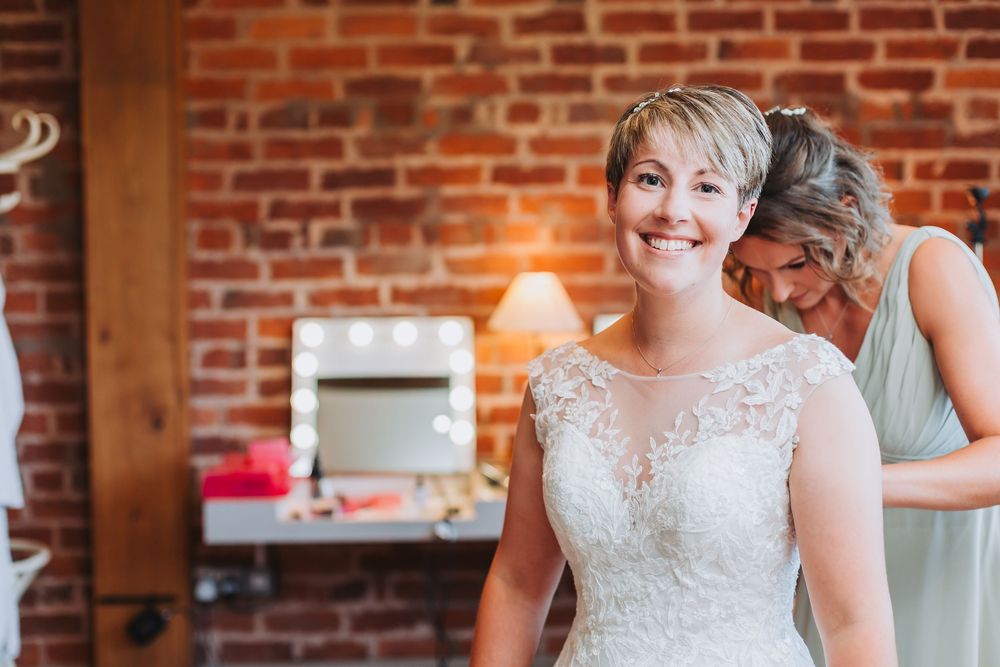 A group stands in a rustic event space with exposed brick walls and warm lighting during preparation for a celebration.