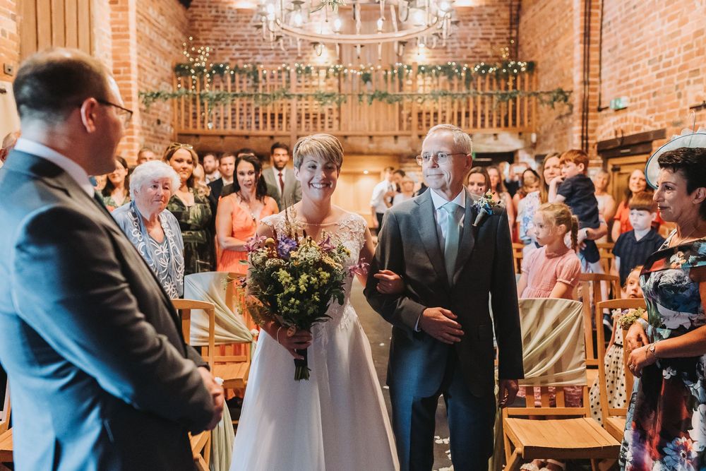 Wedding reception guests enjoy a celebration in a rustic brick and wood beam venue decorated with string lights.