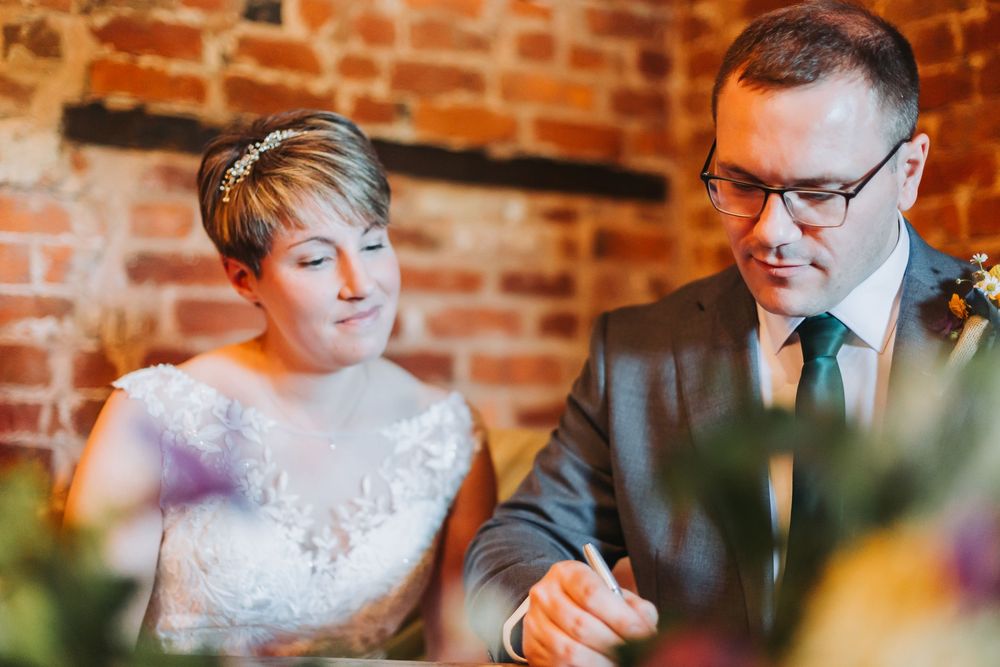 A couple sits at a rustic venue with exposed brick walls during an intimate wedding gathering.