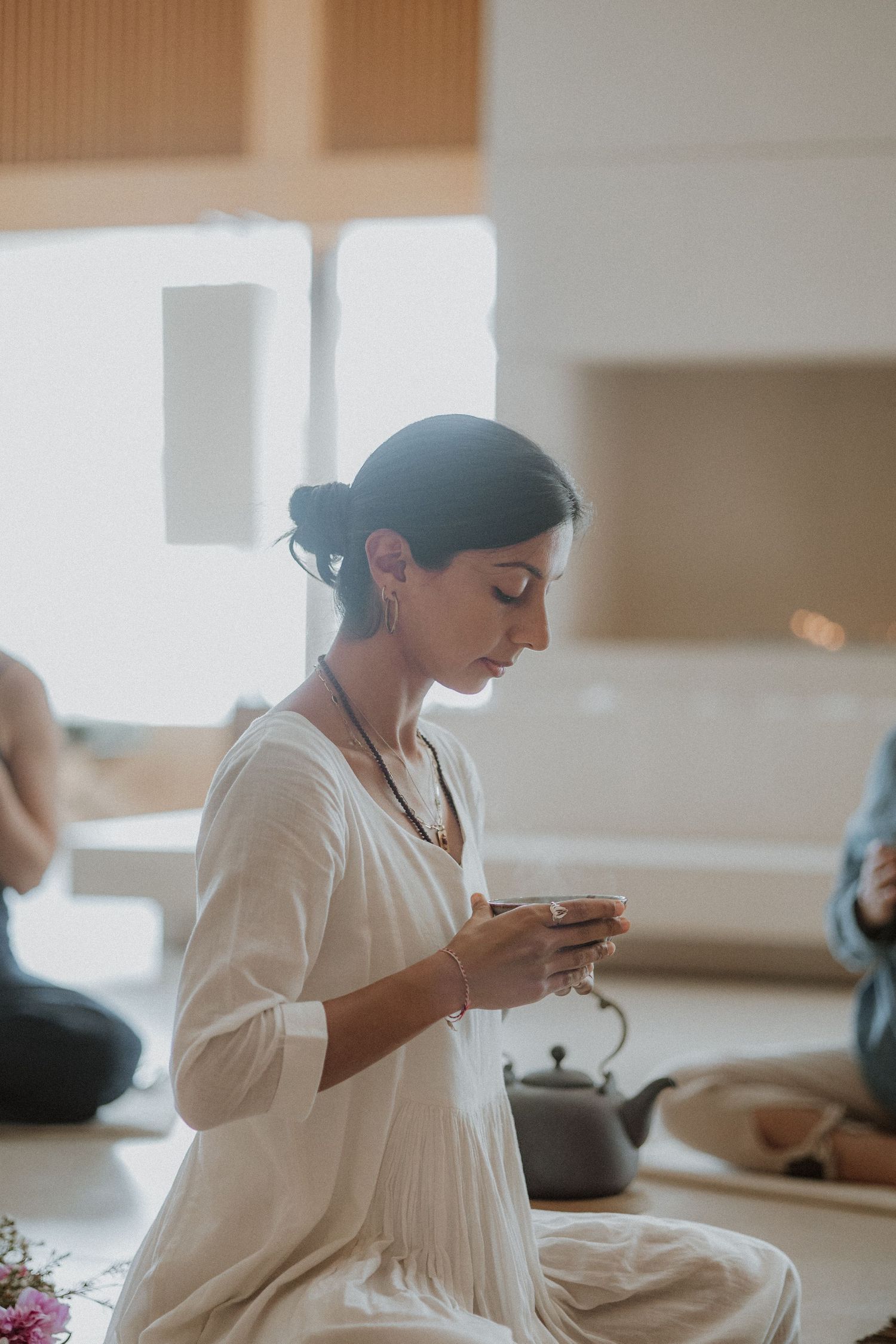Peaceful scene of someone in white dress holding tea cup in serene indoor setting with soft natural lighting.