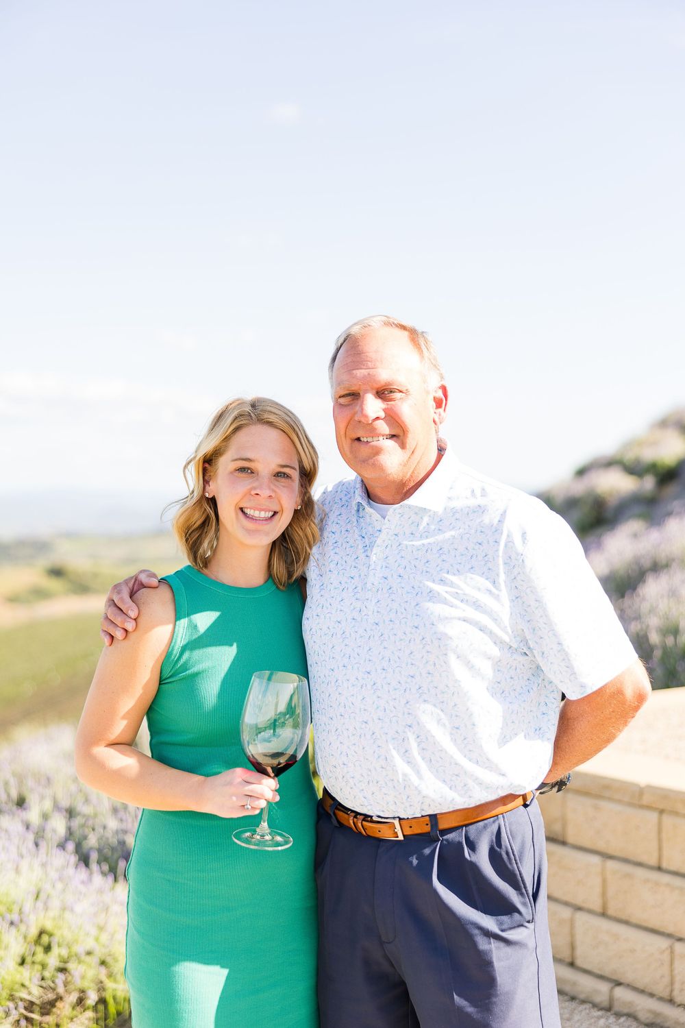 A couple enjoying wine outdoors together near a lavender garden on a sunny day.