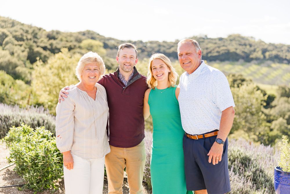 Family group wearing coordinated outfits poses together in a desert landscape during golden hour.