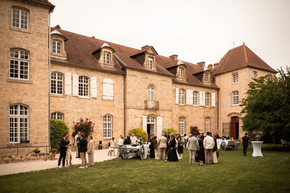 Invités rassemblés devant le château pour le vin d’honneur sous un beau soleil.