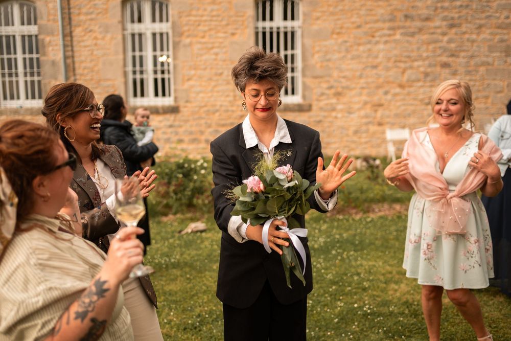 La meilleure amie de la mariée attrape le bouquet, surprise avec une grimace spontanée et drôle.