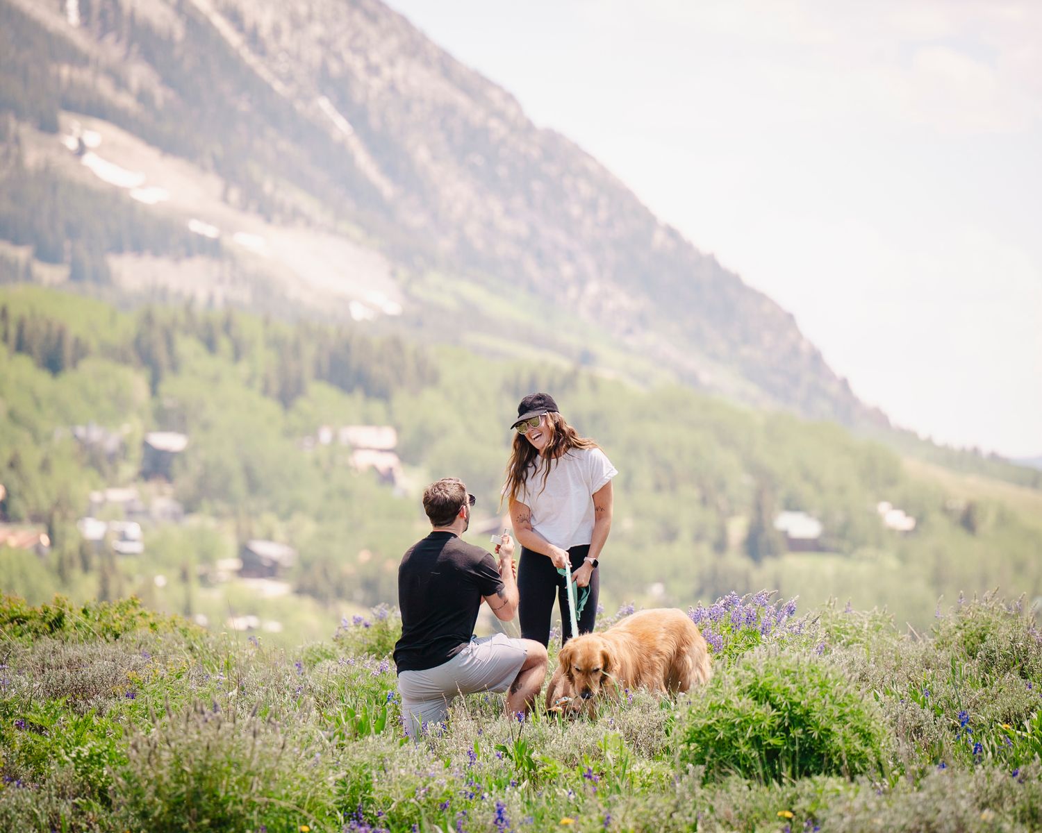 Couple sharing intimate moment with dogs on mountain meadow.