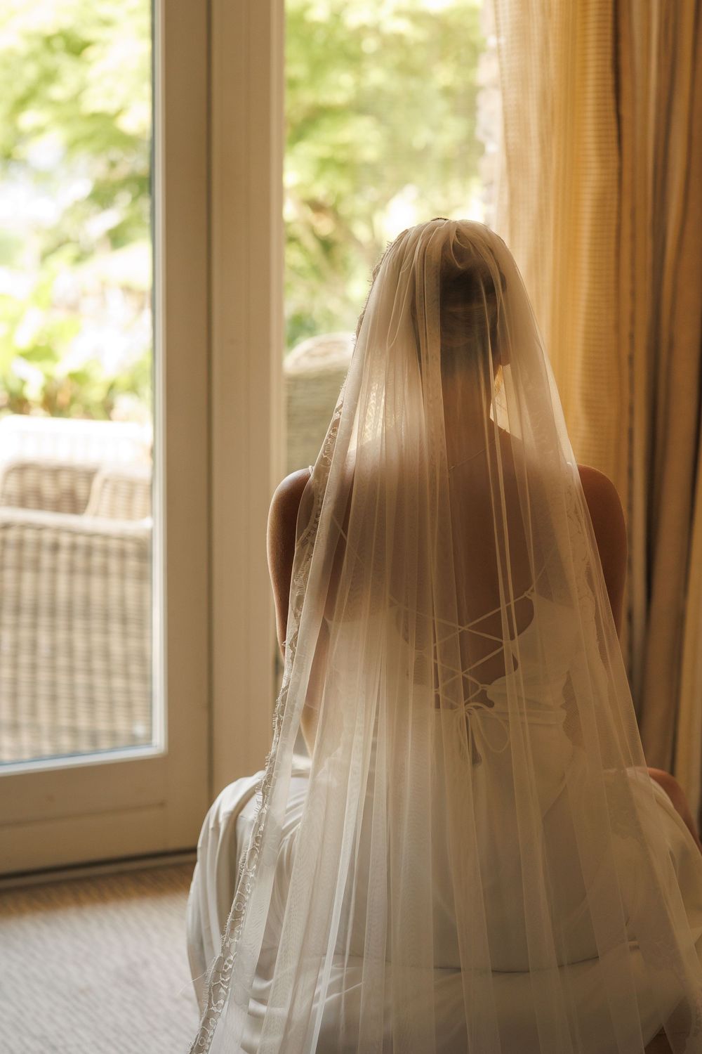 A delicate wedding veil catches sunlight through windows in a bridal preparation room.