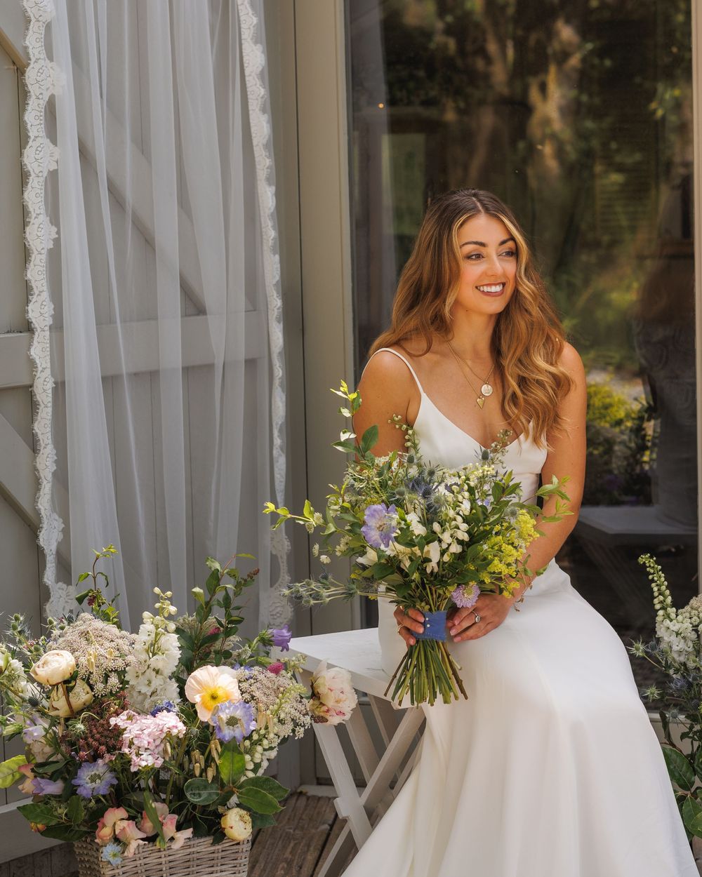 A white wedding dress and floral bouquet are showcased against a rustic porch backdrop.