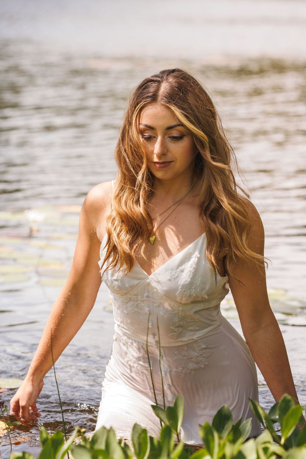 A white wedding dress is captured in an artistic water reflection scene.