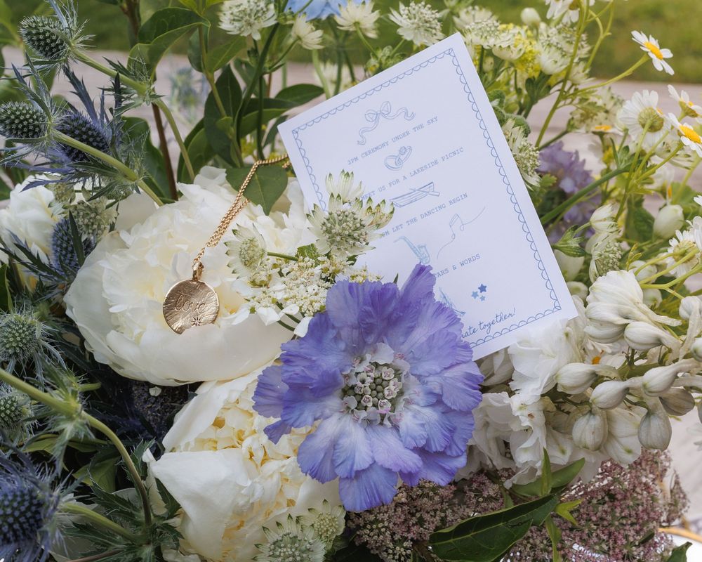 Wedding invitation nestled among white and purple flowers with delicate floral arrangements.