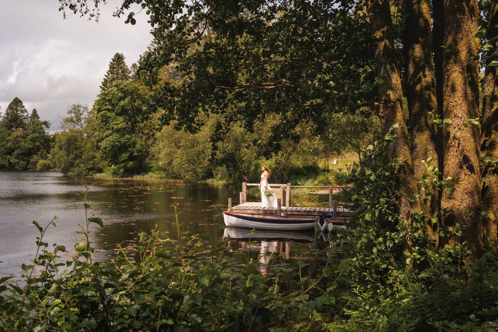 A serene lake view with a wooden dock and trees reflecting in calm waters.
