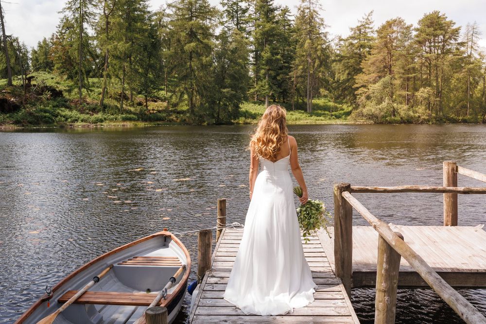 A romantic lakeside scene with a wooden dock and rowboat in natural surroundings.