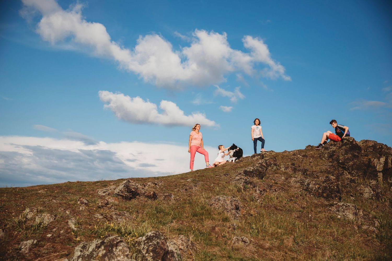 Two people standing on a scenic hilltop overlooking a city landscape as wind blows through blonde hair.