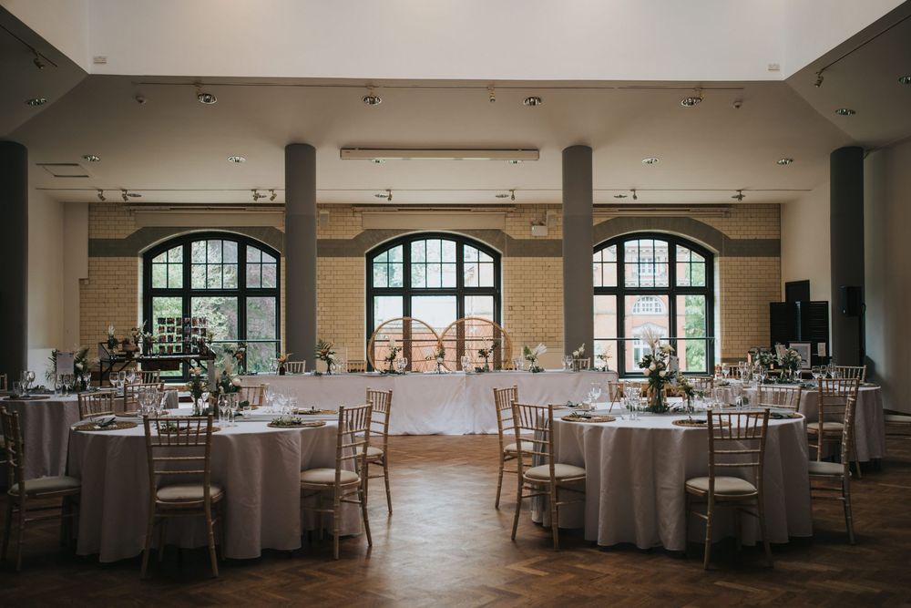 Panoramic view of an elegant banquet hall with round tables and floor-to-ceiling windows letting in natural light.