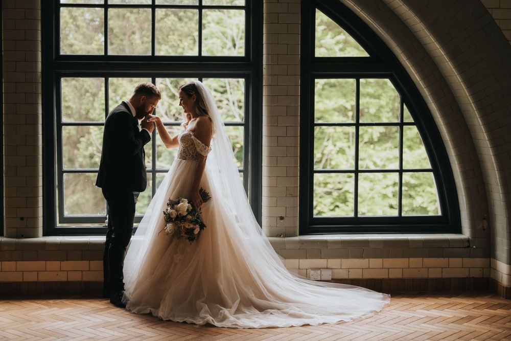 A couple shares a romantic moment in a beautiful arched window setting on their wedding day.