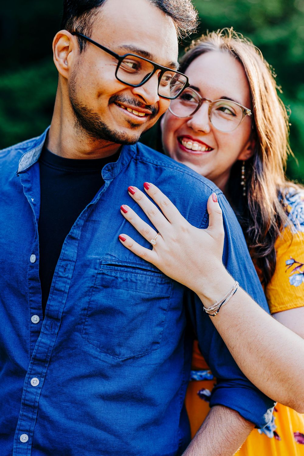A romantic moment between a couple wearing glasses and casual attire while sharing a close embrace outdoors.
