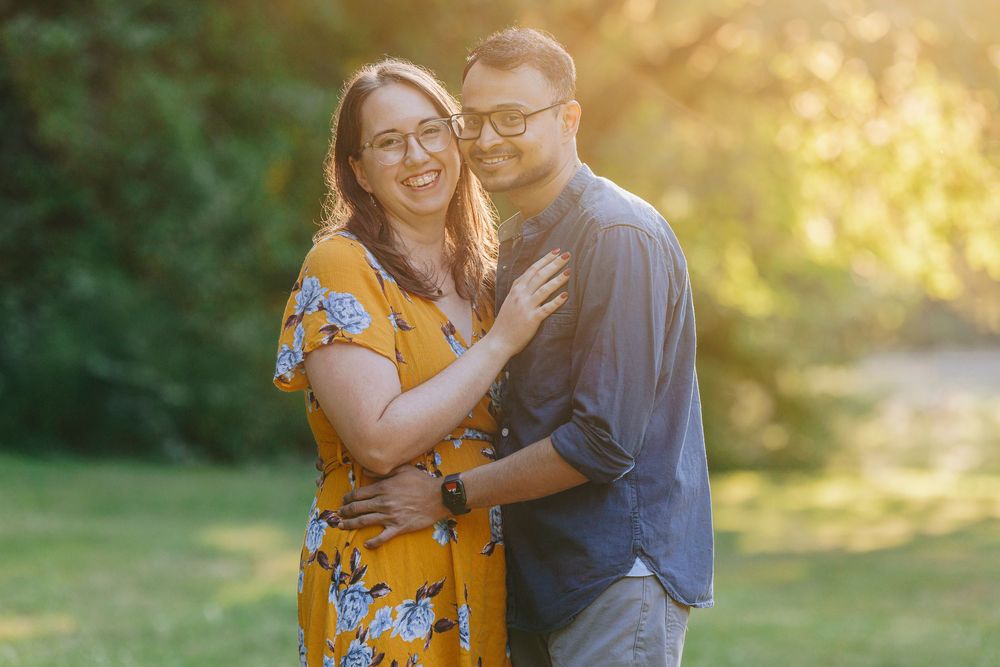 A couple shares tender moments in a sunlit garden setting wearing coordinated yellow and navy outfits.