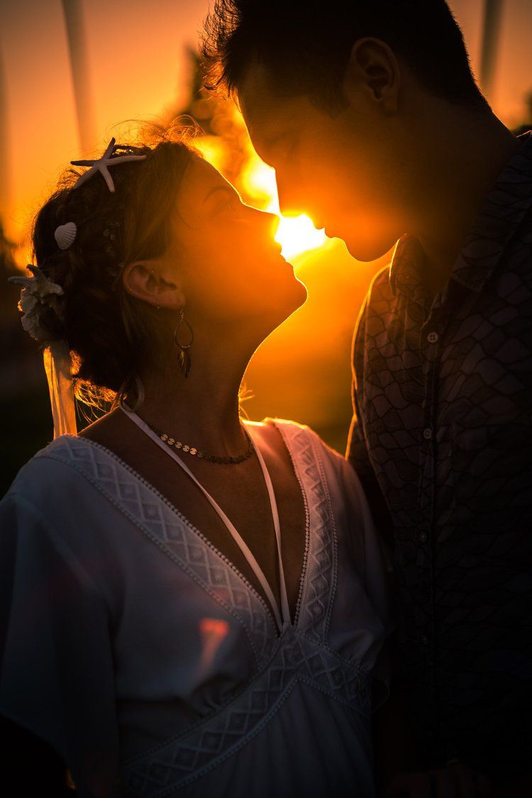 Silhouetted couple in romantic pose against dramatic orange sunset at laguna beach