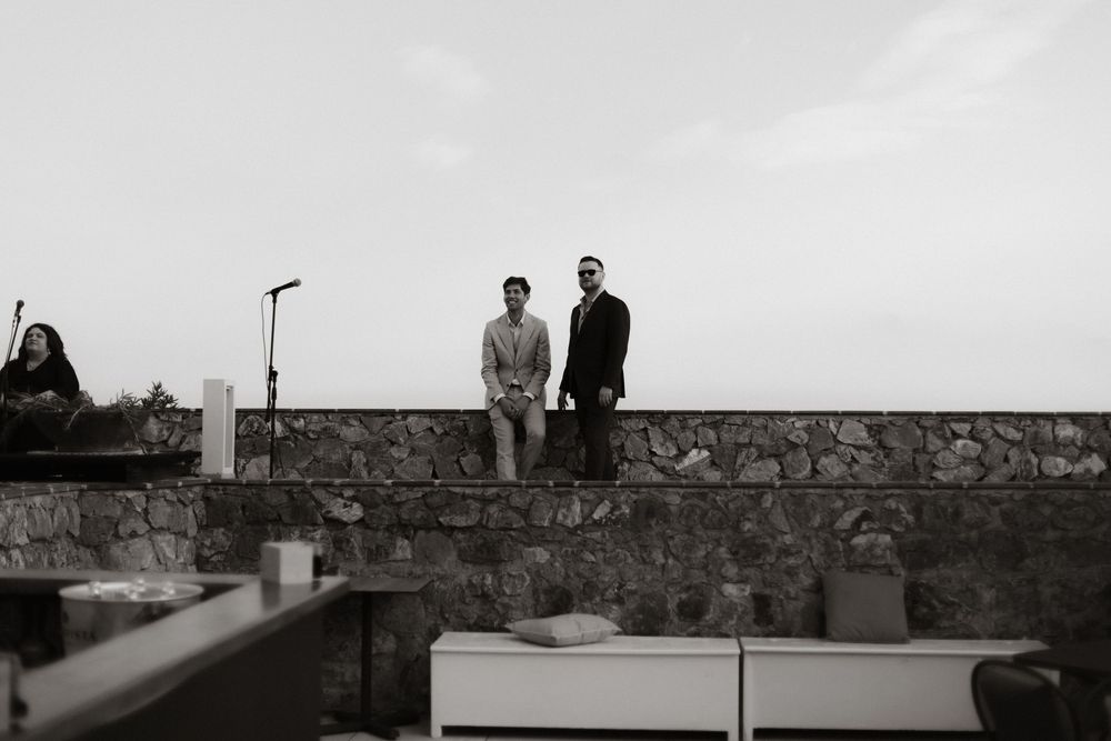 A black and white photograph of two figures standing on a stone wall against an overcast sky.