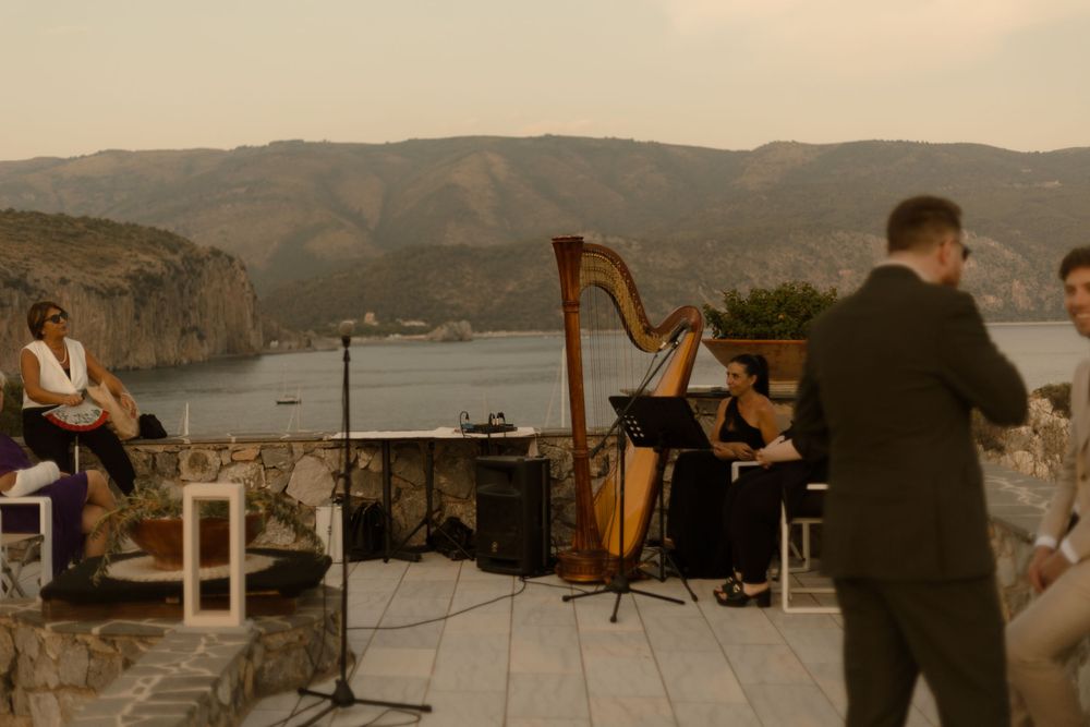 Musicians perform on an outdoor stage overlooking a scenic lake and mountains at sunset.