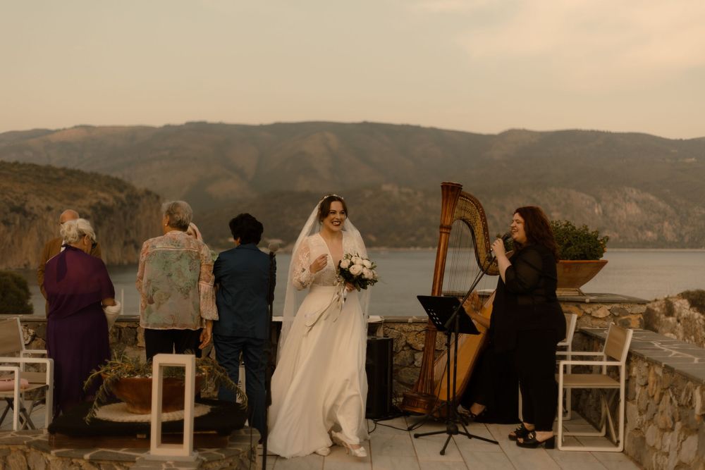 Wedding guests seated at outdoor ceremony overlooking scenic mountain lake at sunset during intimate celebration.
