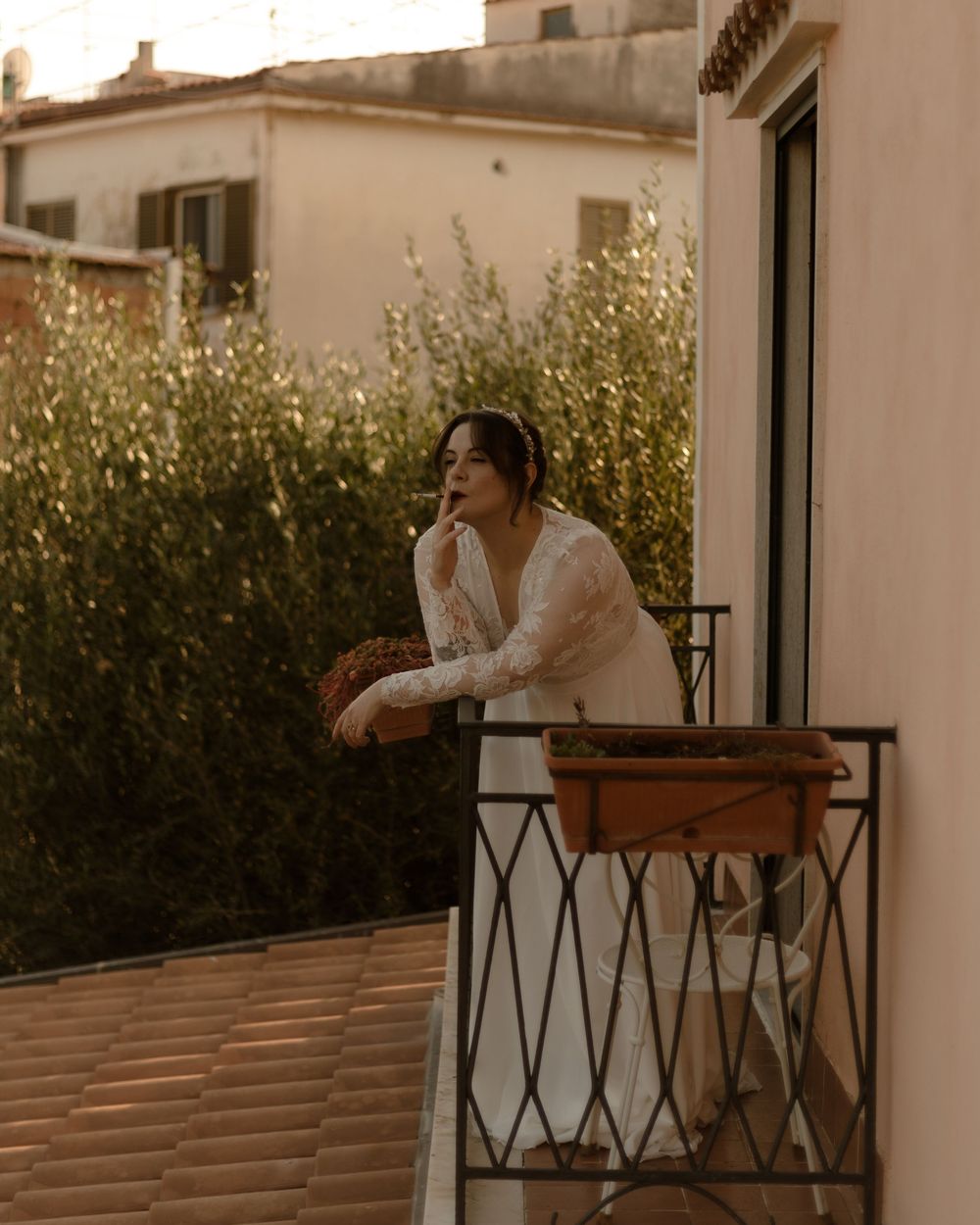 A dreamy golden-hour scene on a Mediterranean balcony with terracotta planters and wrought iron railings.