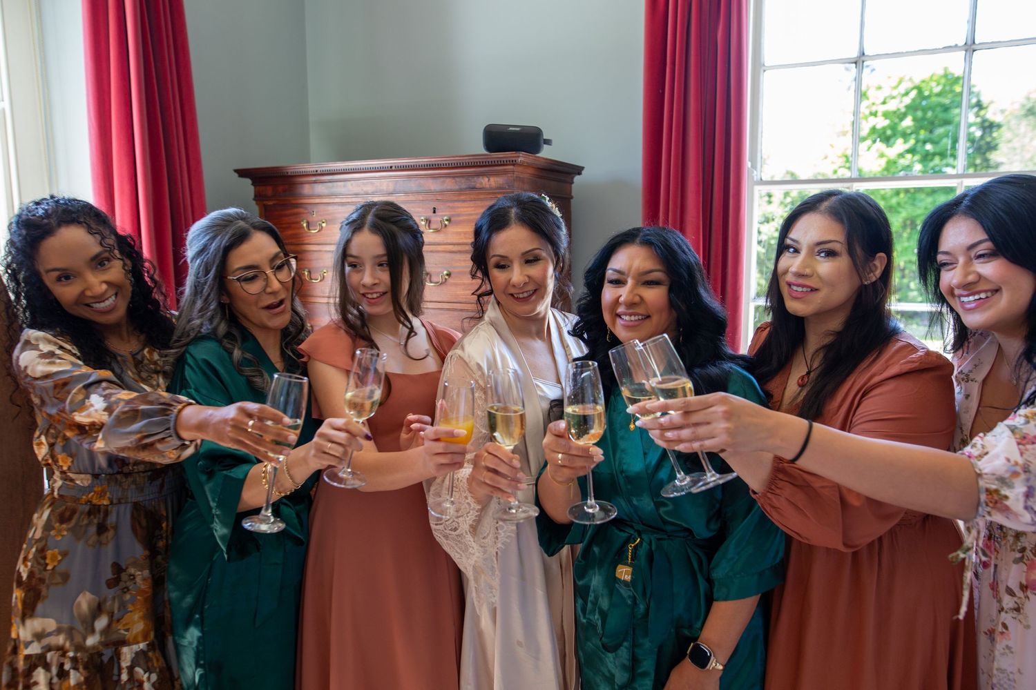 A group of friends in elegant dresses raise their glasses in celebration during a special occasion.