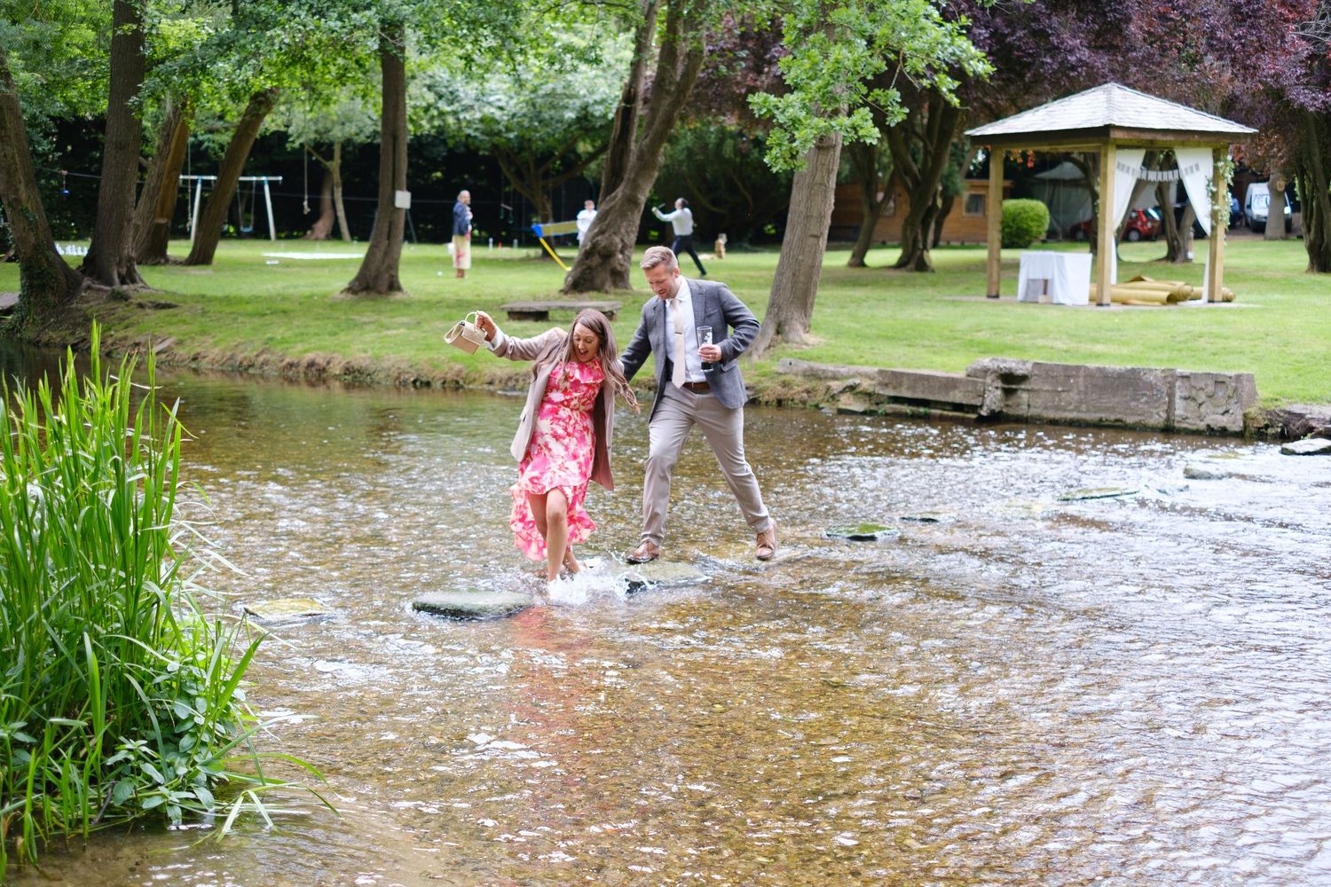 Wedding guest crossing the river on the stepping stones. One is almost falling in!