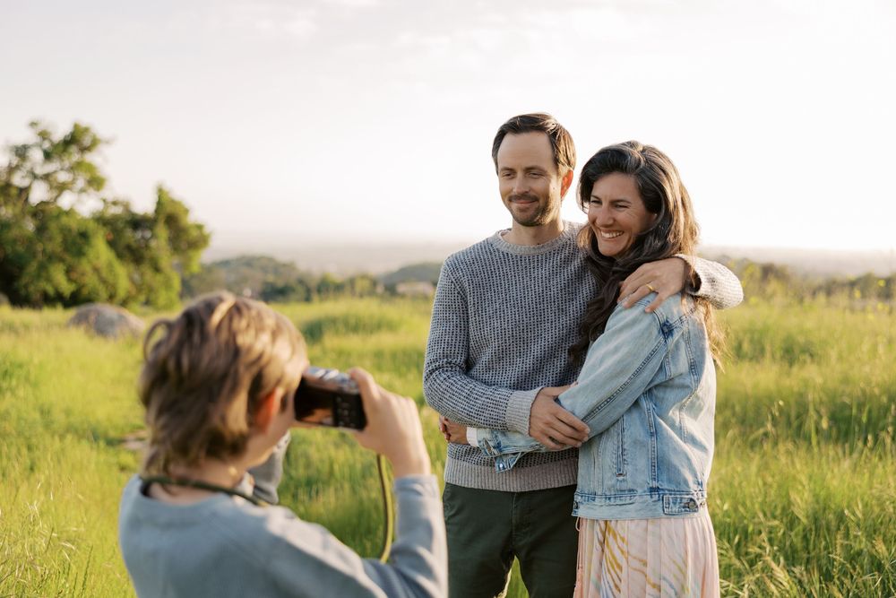 Creative family photo session ideas. Happy couple embraces while standing in a sunlit meadow during golden hour.