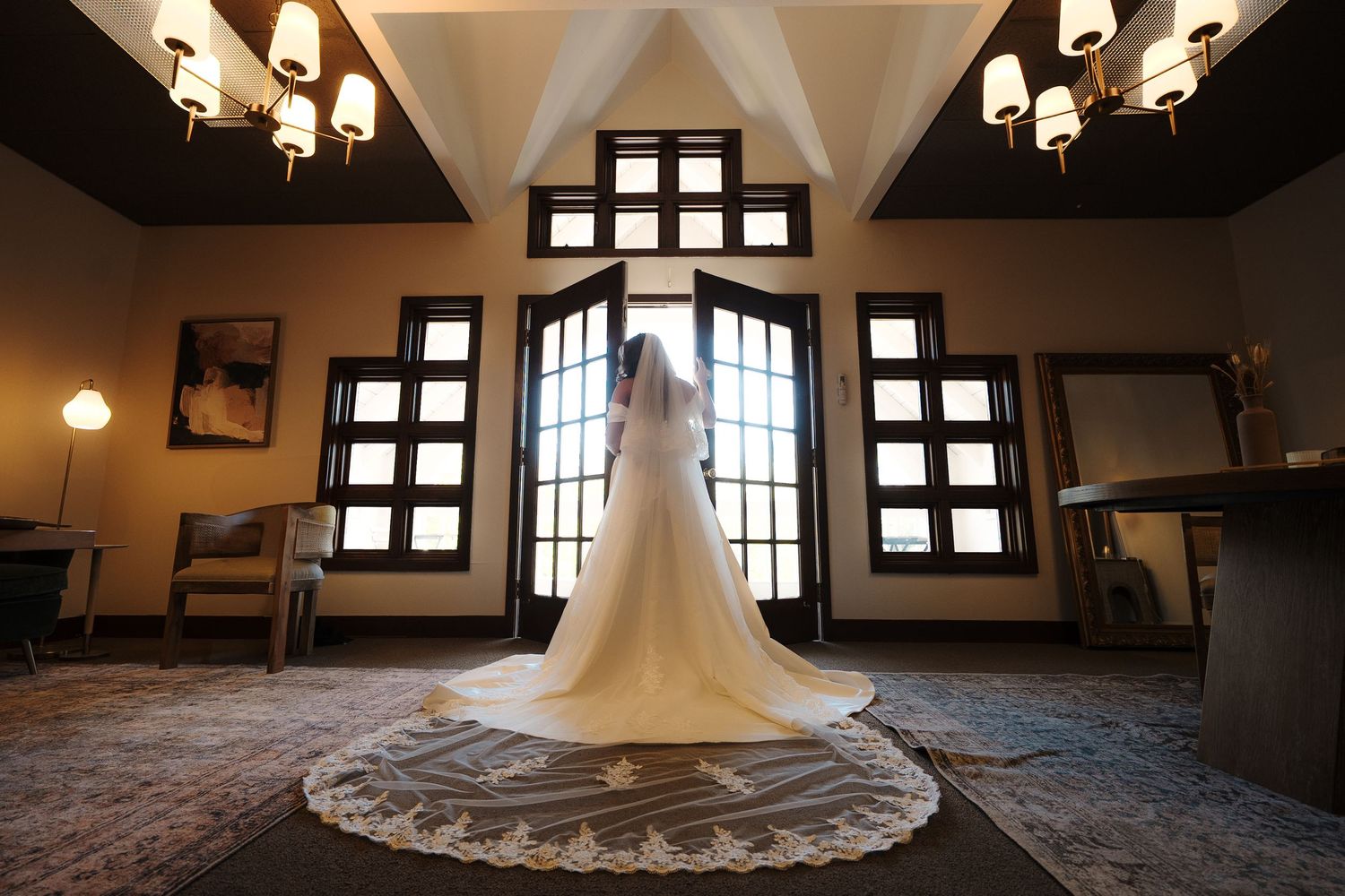 Inner exterior detail of a historic church or chapel with chandelier and wooden beams illuminated by natural light.