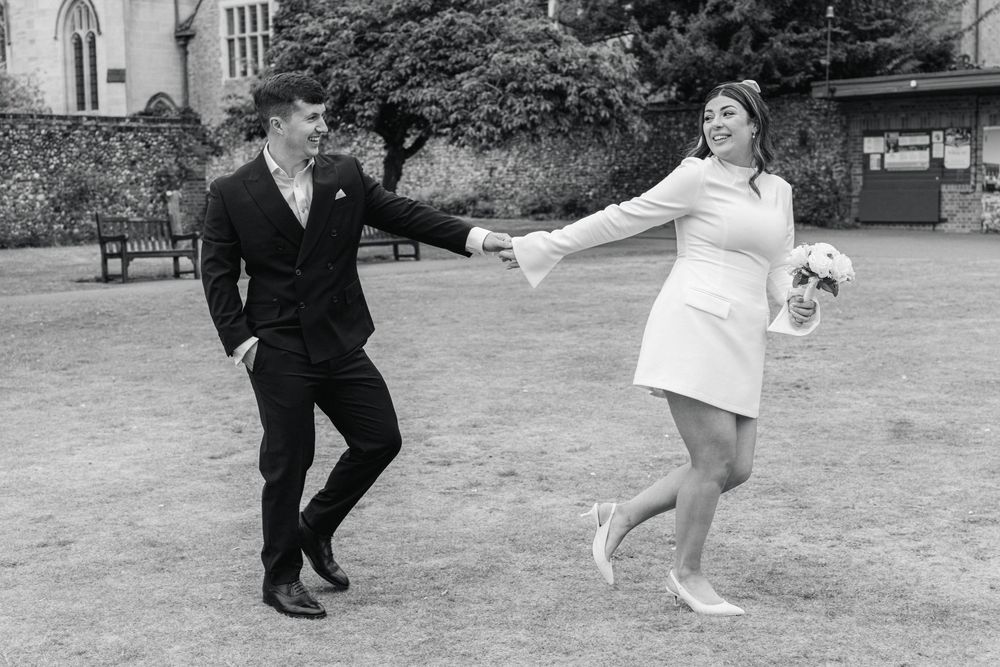 A vintage black and white photo showing two people dancing together outdoors on a grass lawn.