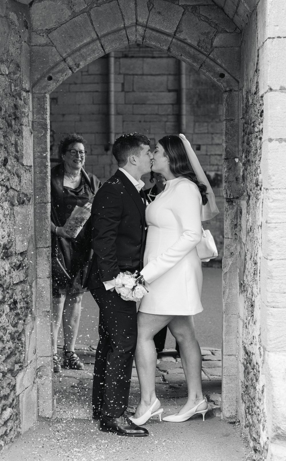 A sequence of three black and white photos showing a wedding couple dancing under rustic stone arches.