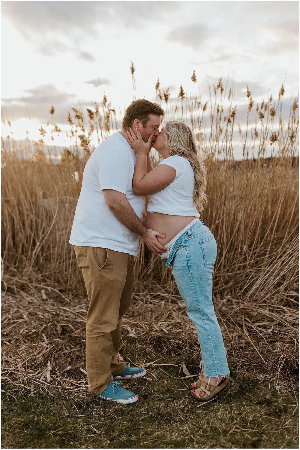 Couple taking maternity photos at the beach in New Hampshire