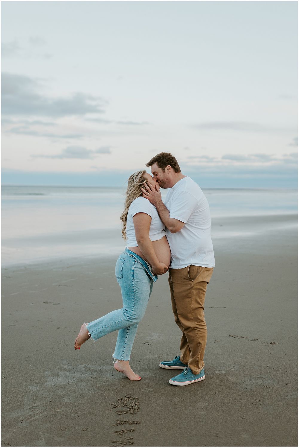 Couple taking pregnancy photos at the beach in New Hampshire
