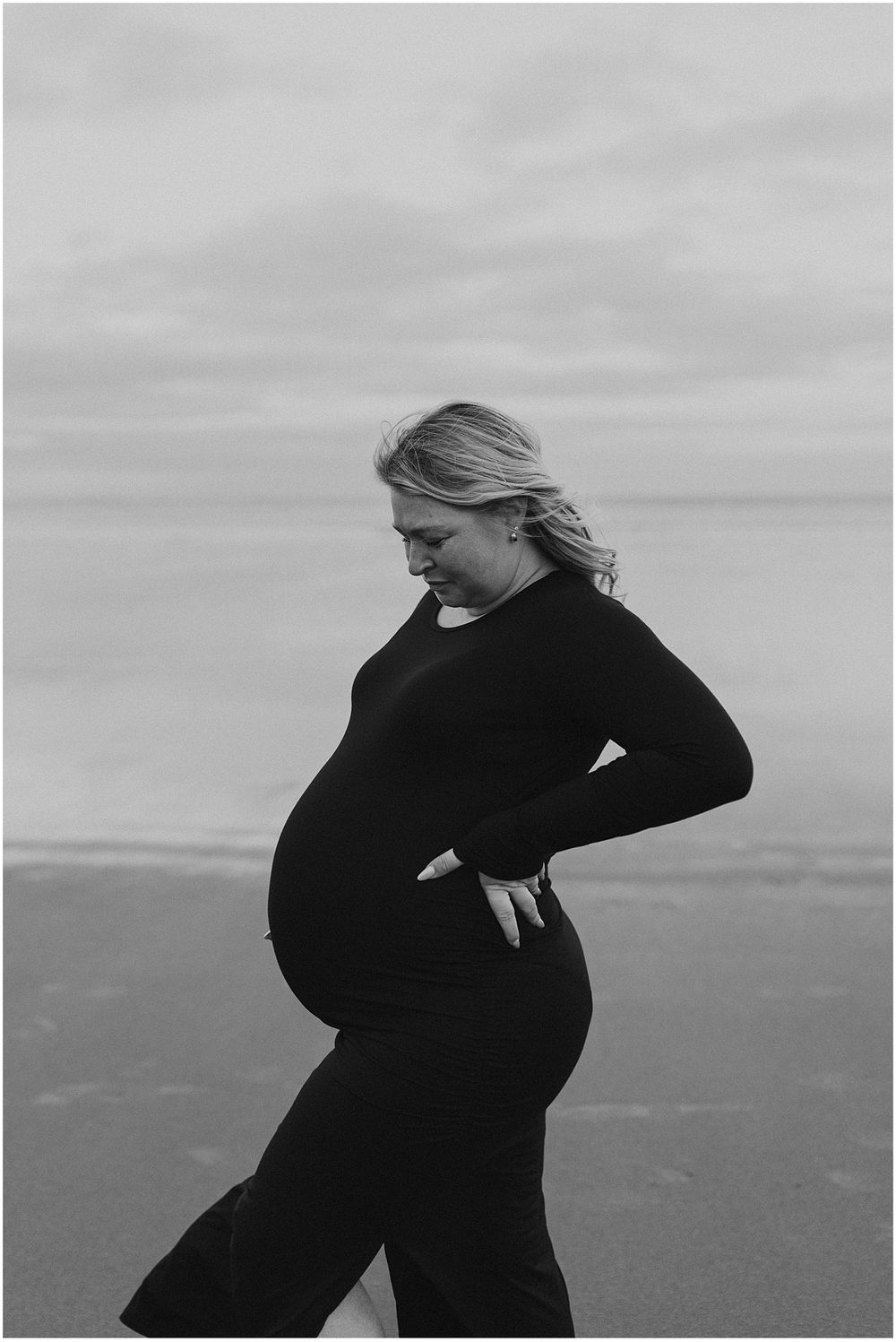 Woman in a black bodycon dress taking maternity photos in New Hampshire