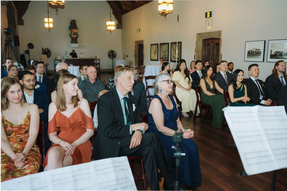 Wedding guests seated in rows facing forward during indoor ceremony.