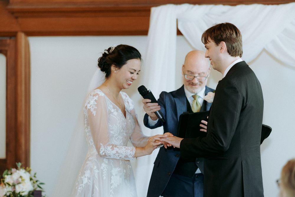 Tender moments exchanged during indoor wedding ceremony with white decor.