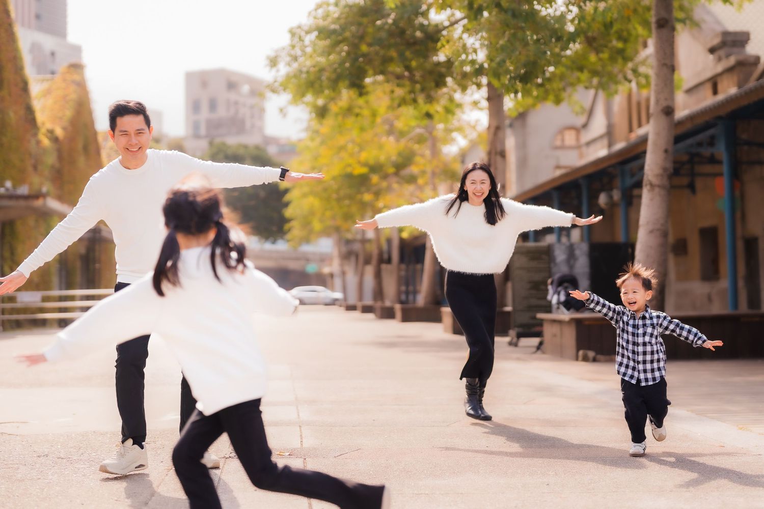 A family runs and laughs together down a bright white hallway wearing coordinated blue and navy outfits.