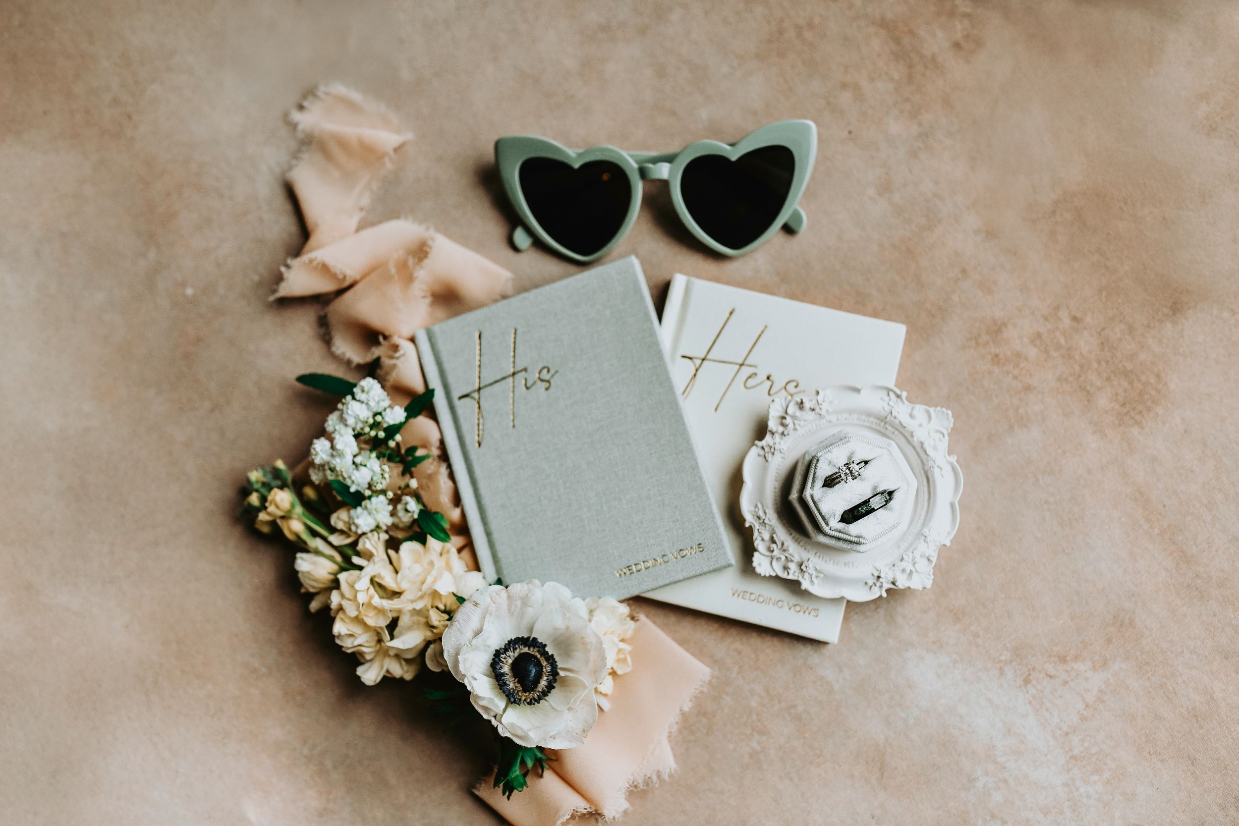 Close-up flat lay of bride’s shoes, wedding rings, and bridal bouquet, surrounded by delicate greenery and spring florals for wedding flat l
