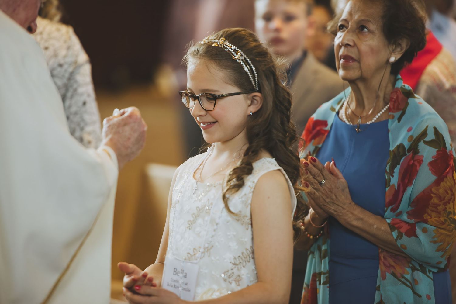 Young parishioner and congregation members during Catholic Mass service gather around as worship begins.