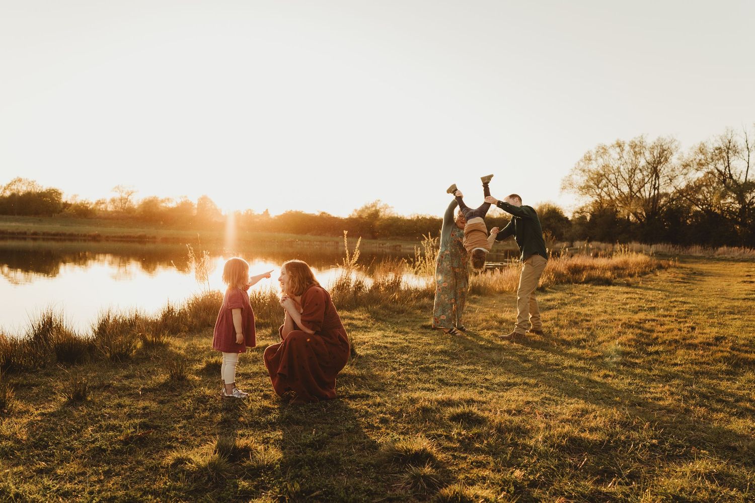 A group enjoying a scenic sunset by the lake as golden light streams through the trees and reflects on the water.