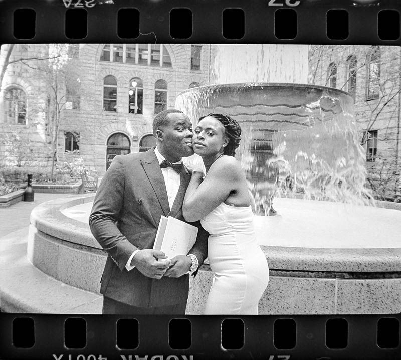 A romantic couple in formal attire photographed on 35mm film near an ornate fountain at Allegheny County Courthouse in Pittsburgh PA